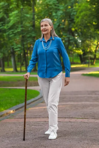 Senior woman with walking cane in park