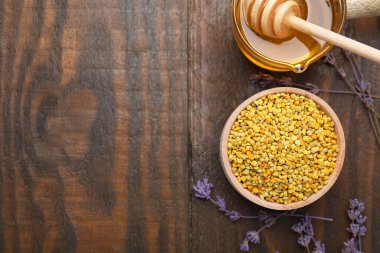 Düz kompozisyon, taze arı polenleri ve ahşap masa üzerinde bal. Metin için boşluk