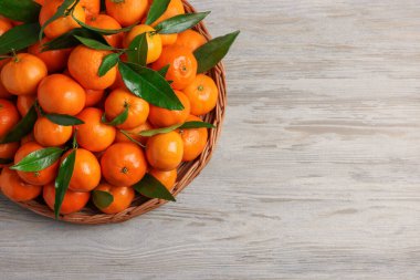 Beyaz ahşap masada taze, sulu mandalina ve yeşil yapraklar. Metin için boşluk