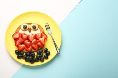 Çocuklar için yaratıcı hizmet. Krep, böğürtlen, krema, muz ve badem renginde baykuş tabağı, üst manzara. Metin için boşluk