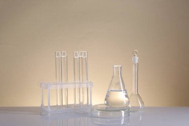 Laboratuvar analizi. Bej arkaplanda farklı cam eşyalar