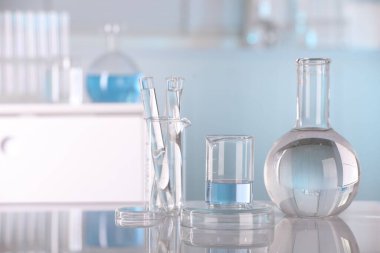 Laboratuvar analizi. Beyaz masa üzerinde sıvı bulunan farklı cam eşyalar, metin için boşluk.