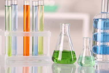 Laboratuvar analizi. Beyaz masadaki sıvılarla bulanık arka planda farklı cam.