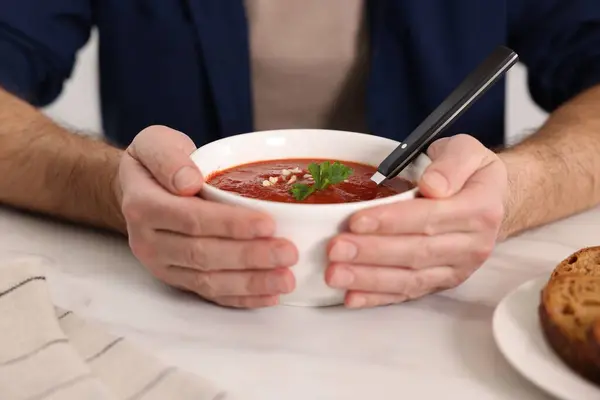 Man with delicious tomato soup at light table, closeup
