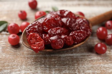 Lezzetli kuru kızılcıklar kaşıkta ve taze olanlar kırsal ahşap masada, yakın plan.