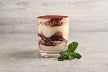 Cam kaplı nefis tiramisu ve gri desenli masada nane şekeri.