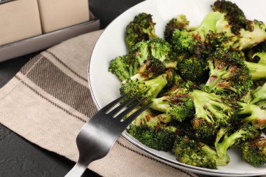 Lezzetli kızarmış brokoli ve çatal siyah masada, yakın plan.