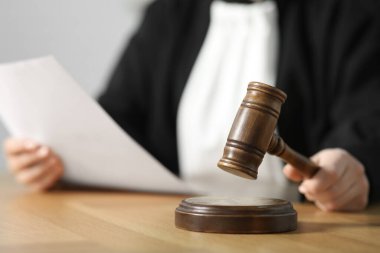 Yargıç, mahkeme salonundaki ahşap masaya tokmak vuruyor, yakın plan.