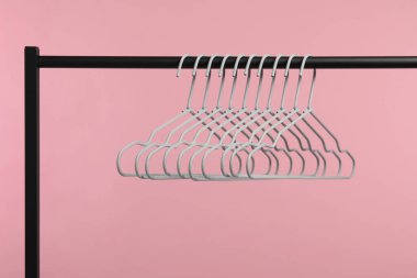 Boş elbise askıları pembe arka planda asılı