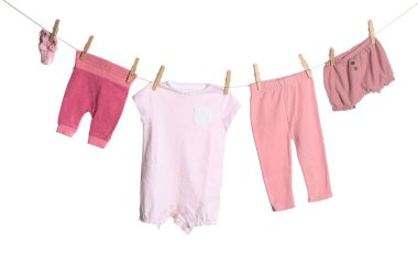 Different baby clothes drying on laundry line against white background
