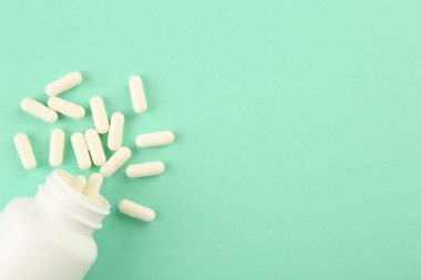 Turkuaz arka planda şişe ve vitamin kapsülleri, üst manzara. Metin için boşluk