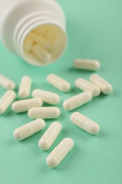 Turkuaz arka planda şişe ve vitamin kapsülleri, yakın plan