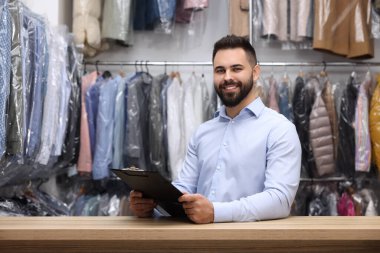 Kuru temizleme servisi. Kapalı alanda pano tutan mutlu işçi.
