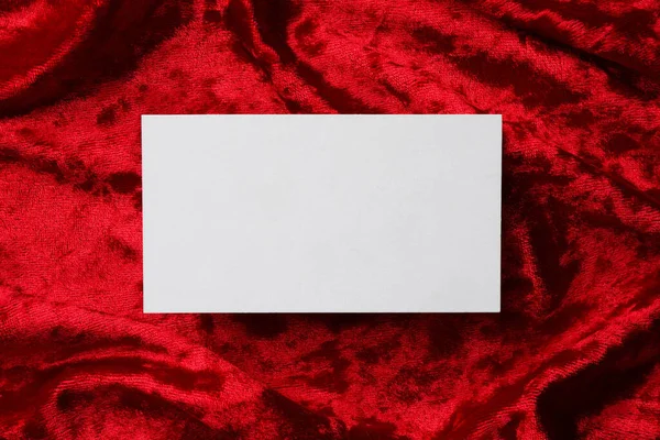 Blank business card on red fabric, top view. Mockup for design