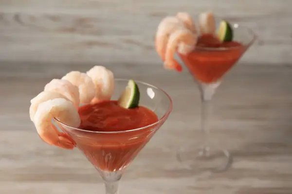 Tasty shrimp cocktail with sauce in glasses on wooden table, closeup