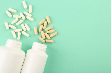 Şişeler ve turkuaz arka planda farklı vitamin kapsülleri, düz yatak. Metin için boşluk