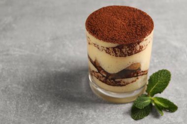 Cam kaplı nefis tiramisu ve gri desenli masada nane şekeri, yakın plan. Metin için boşluk