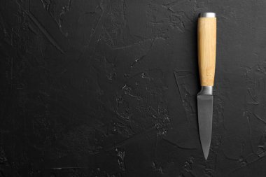 Koyu dokulu bir masada keskin bir bıçak, üst görüş. Metin için boşluk