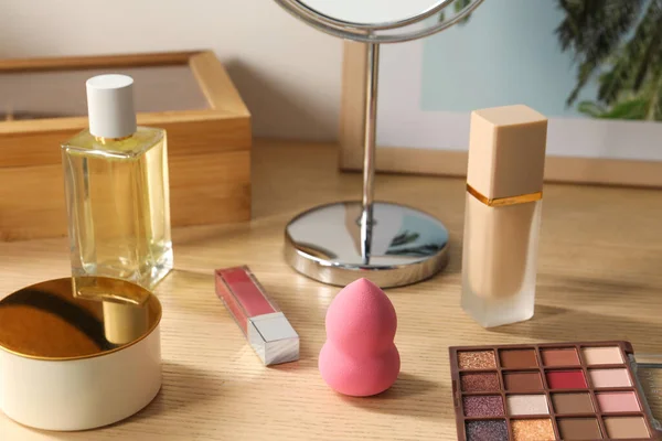 Makeup products and perfume on wooden dressing table