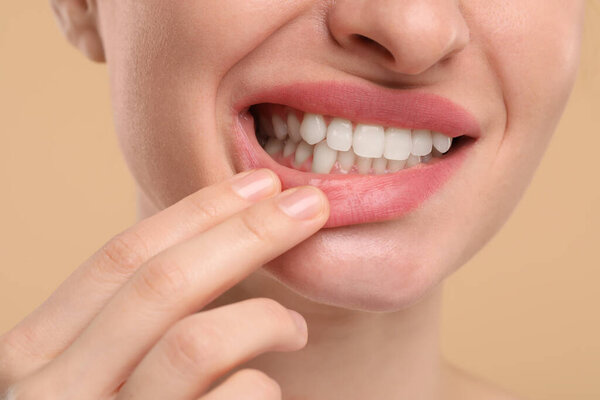 Woman showing her clean teeth on beige background, closeup