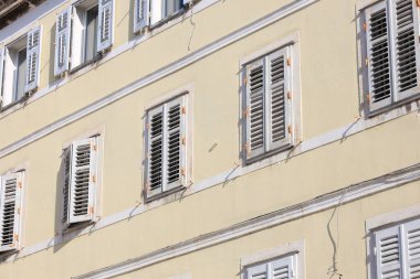 Pencereleri ve ahşap panjurları olan eski bir apartman.