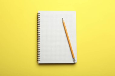 Sarı arkaplandaki defter ve kalem, üst görünüm