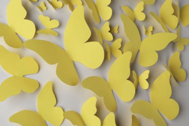 Açık gri arka planda sarı kağıt kelebekler, üst manzara