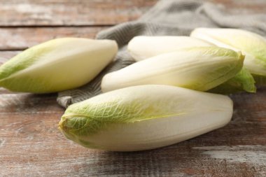 Fresh raw Belgian endives (chicory) on wooden table, closeup clipart