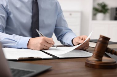 Ofisteki ahşap masada belgelerle çalışan avukat, yakın plan.