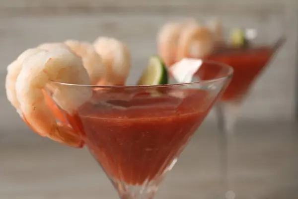 Tasty shrimp cocktail with sauce in glasses on table, closeup