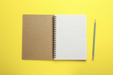 Sarı arkaplandaki defter ve kalem, üst görünüm