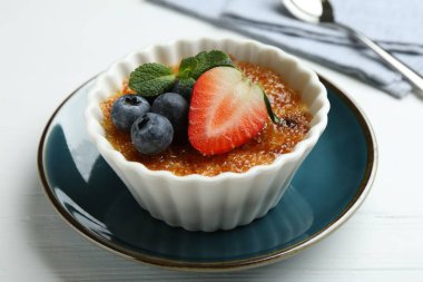 Böğürtlenli ve nane şekerli nefis creme brulee beyaz ahşap masada, yakın plan.