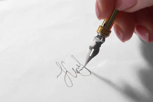 Woman signing on sheet of paper with fountain pen, closeup