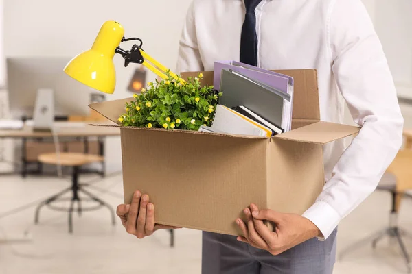 Unemployment problem. Man with box of personal belongings in office, closeup