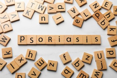 Tahta karelerden yapılmış kelime sedef hastalığı. Beyaz masa üzerinde harfler var.