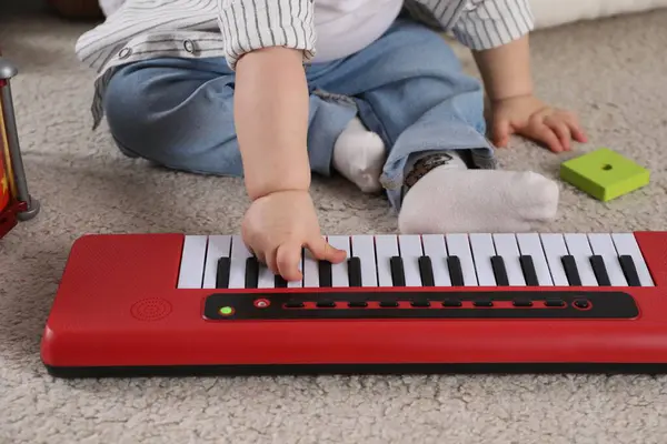 Little child playing toy piano indoors, closeup