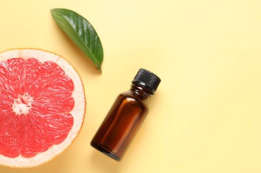 İçinde greyfurt yağı, yaprak ve soluk sarı arka planda taze meyve bulunan bir şişe. Metin için boşluk