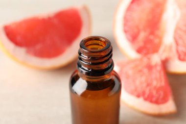Şişede greyfurt yağı ve masada meyve, yakın plan.