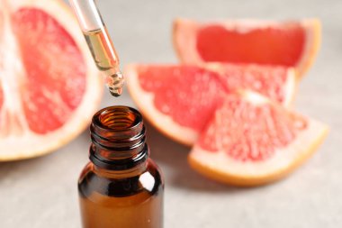 Pipetten şişeye greyfurt yağı damlatıyor ve ışık masasının üzerine taze meyve döküyor. Metin için boşluk
