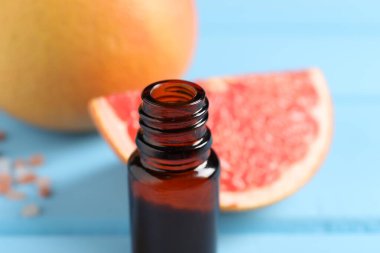 Şişedeki greyfurt yağı açık mavi masada, yakın plan.