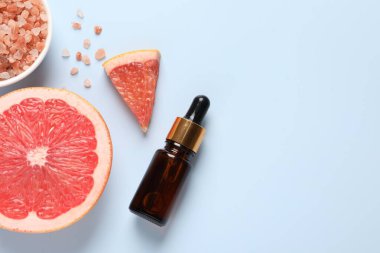 Şişede greyfurt yağı, deniz tuzu ve açık mavi masada meyve kesimi. Metin için boşluk