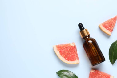 Şişede greyfurt yağı, yapraklar ve açık mavi masada meyve kesimi. Metin için boşluk