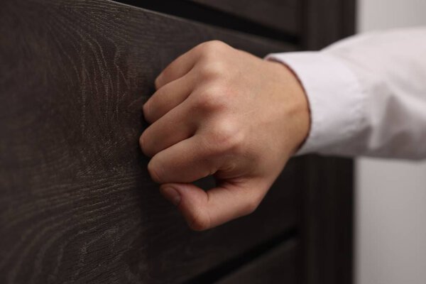 Collector knocking on door indoors, closeup view