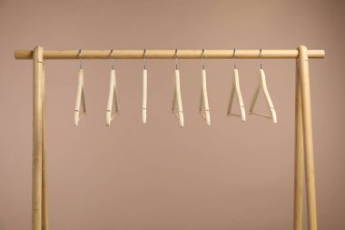 Boş elbiseler, açık kahverengi arka planda ahşap askılarda asılı.