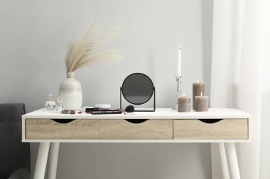 Aynalı giyinme masası, kozmetik ürünler, parfümler ve makyaj odasında yanan mumlar.