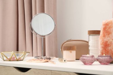 Aynalı giyinme masası, kozmetik ürünler, mücevherler ve makyaj odasında yanan mumlar.