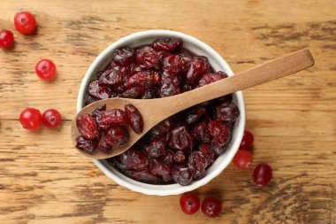 Lezzetli kuru kızılcıklar kasede ve taze olanlar ahşap masada, üst manzara.