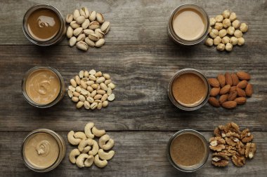 Kavanozlarda lezzetli fındık ezmesi ve ahşap masada çiğ fındık.