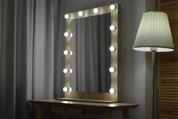 Beautiful mirror with light bulbs and lamp in makeup room