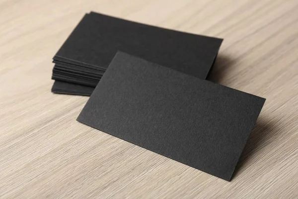 Blank black business cards on wooden table, closeup. Mockup for design